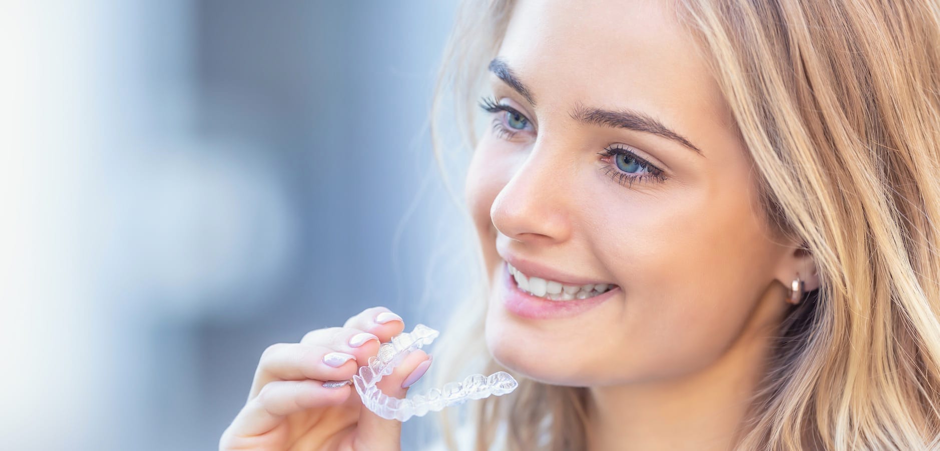 Woman smiling, holding clear aligners Woman smiling, holding clear aligners